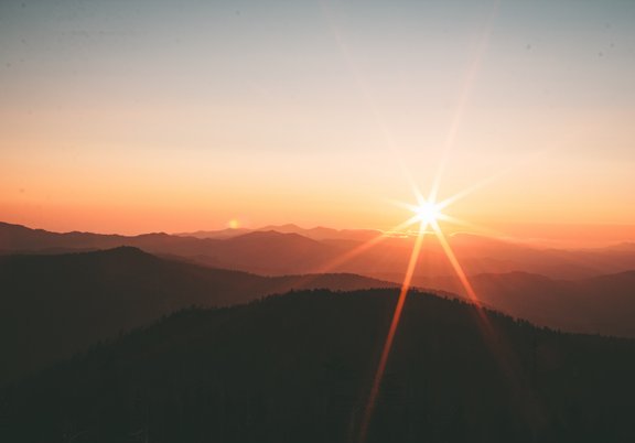 Das Bild zeigt einen Berghorizont hinter dem gerade die Sonne untergeht.